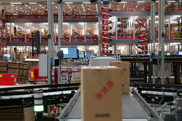 Boxes moving along a conveyor with Ambaflex spiral elevators in the background